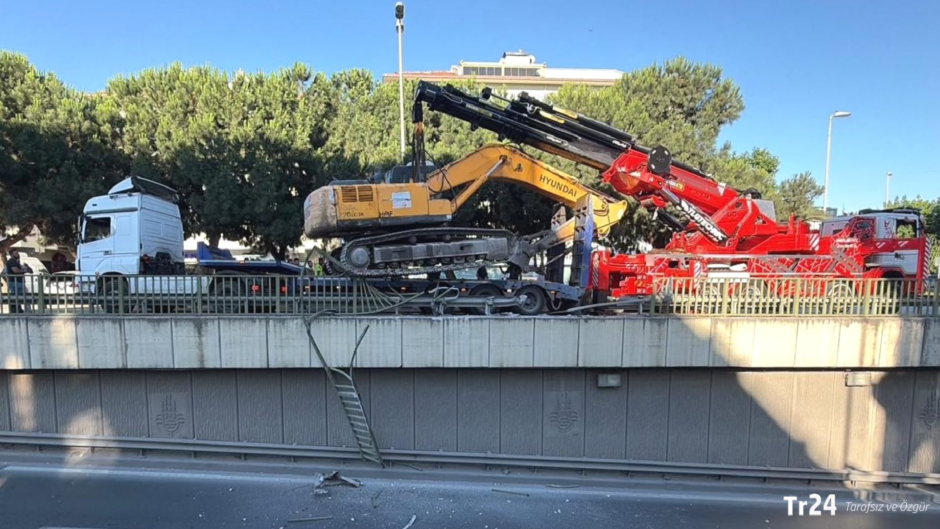 Seyir halindeki TIR’ın üzerinden düşen ekskavatör korkuluklarda asılı kaldı